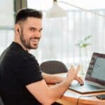 VOIP Smiling Man on Laptop Pointing – Exploring VoIP Phone Systems for Business in Portland