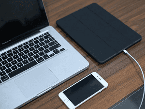 A laptop, iPhone, and iPad on a table.