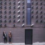 proactive-cybersecurity Two women conducting a cybersecurity risk assessment in Portland, gazing up at a wall of cameras.