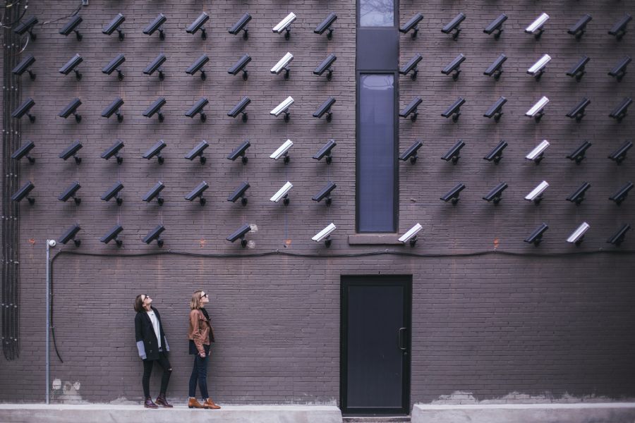 Two women conducting a cybersecurity risk assessment in Portland, gazing up at a wall of cameras.