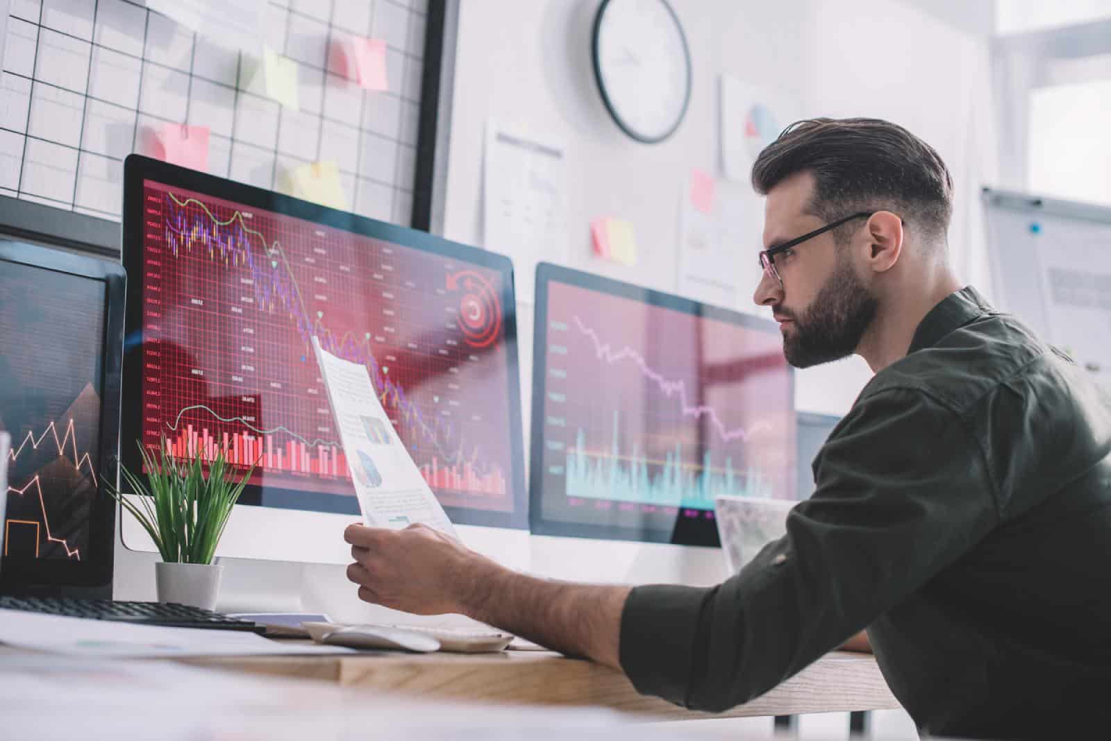 A man is analyzing charts on computer screens.