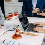 business people and lawyers discussing contract papers sitting at the table. Concepts of law, advice, legal services. A group of professionals gathered around a desk in an office, engaged in discussion and collaboration.