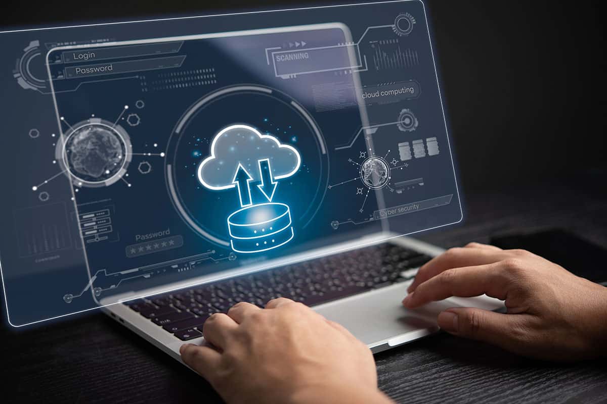 A businessman is using a laptop showing an icon of a data server uploading to a cloud.